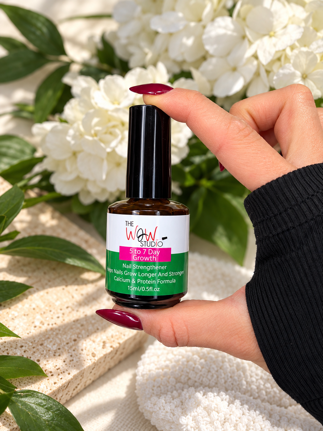 The WOW Studio Nail Strengthener lifestyle photo with manicured hand and flowers